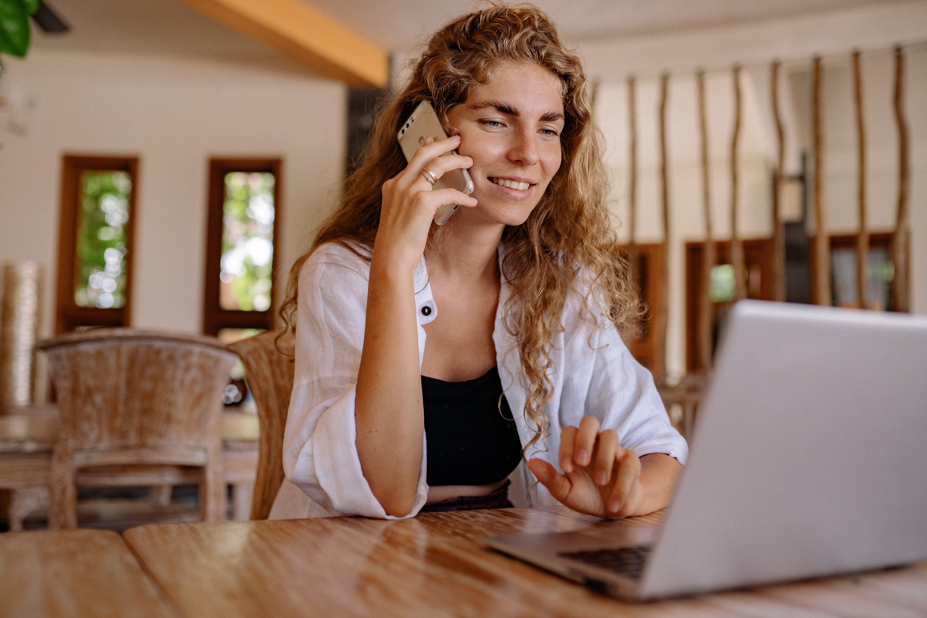 Mujer hablando por teléfono mientras mira una laptop gracias a la gestión de canales