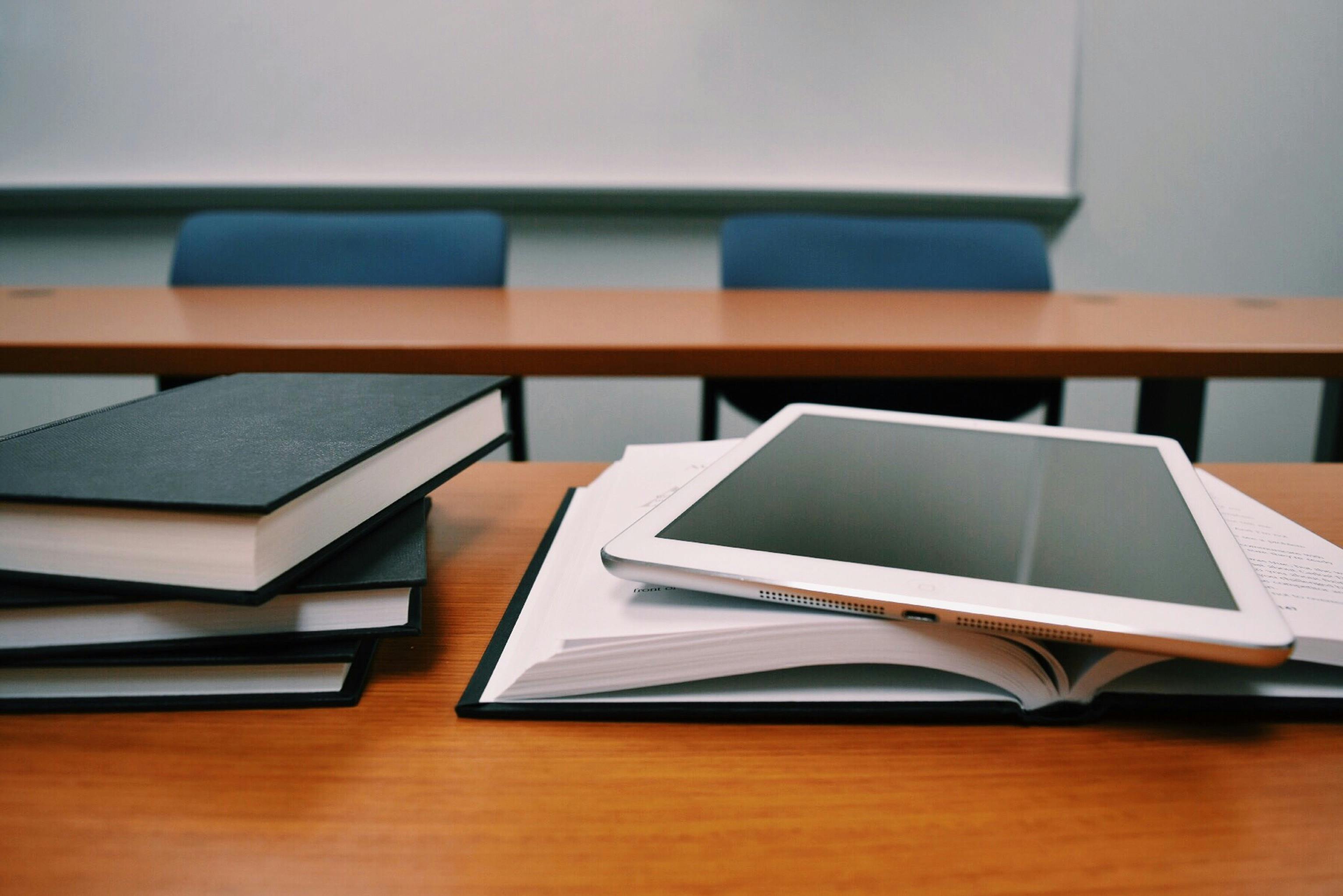 Libros y una tablet sobre un escritorio simboliando la gestión administrativa en instituciones educativas.